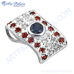 Load image into Gallery viewer, Sterling silver pendant with central blue sapphire and surrounding red garnet gemstones.