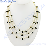 Load image into Gallery viewer, Pearl and gemstone beaded necklace on a white display stand. Features white pearls and dark teardrop-shaped gemstones.
