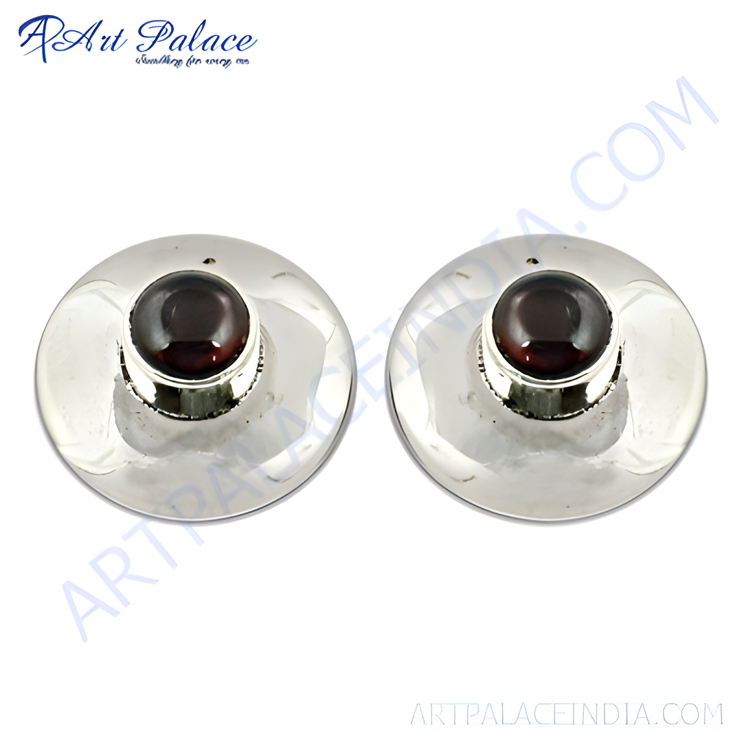 Sterling silver stud earrings with a round, deep red garnet gemstone center on a polished surface