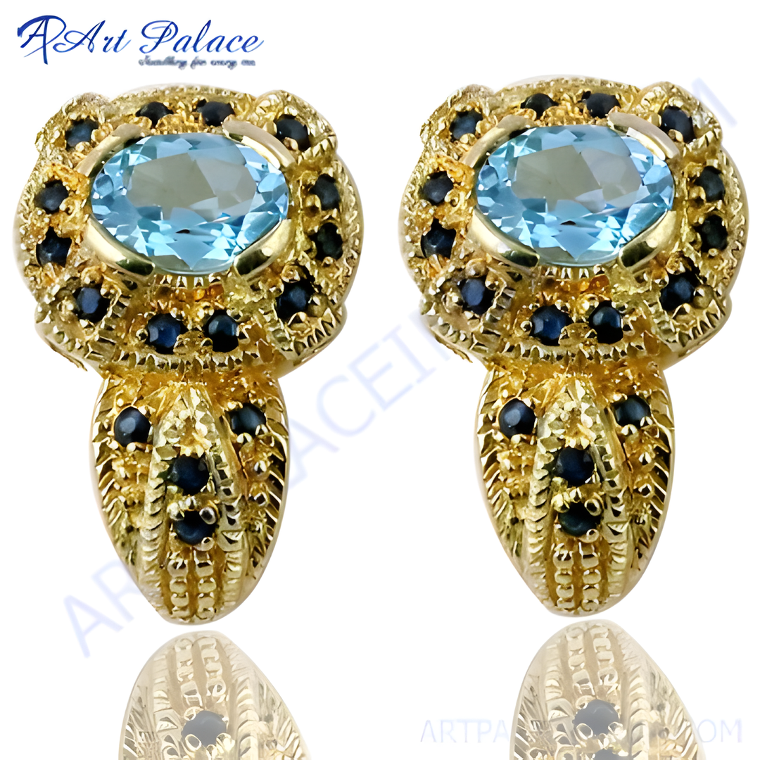 Gold stud earrings with a large oval blue topaz center stone and sapphire accents