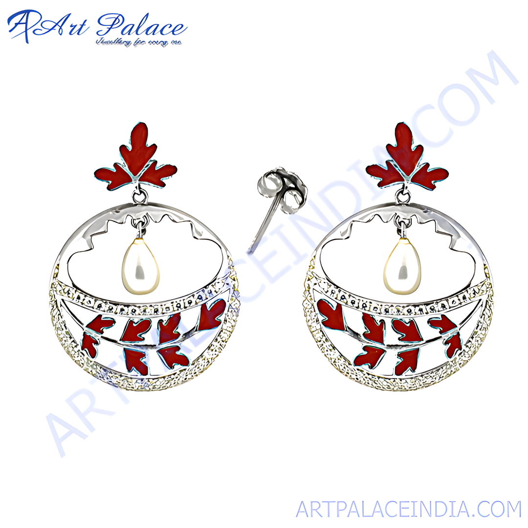 Silver drop earrings with red enamel leaf design and white background.