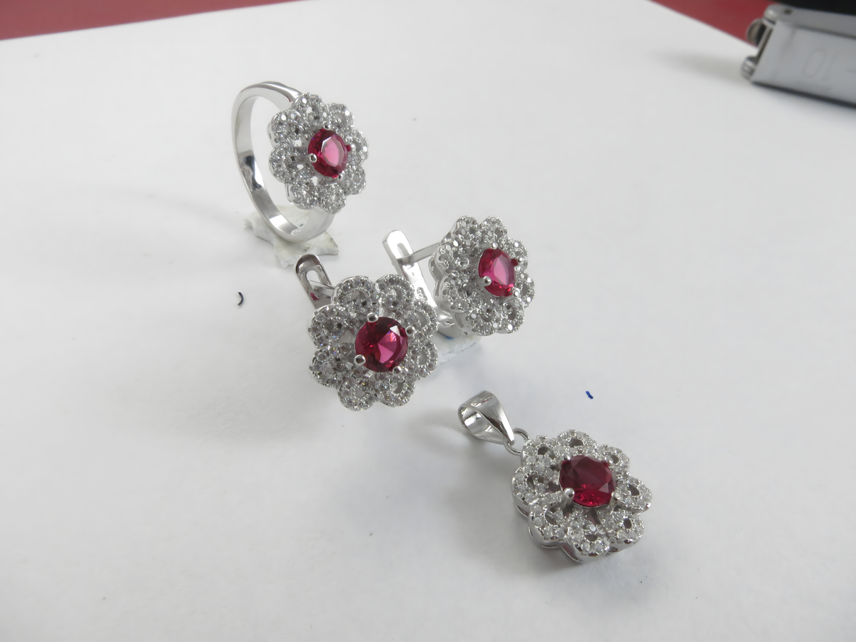 925 sterling silver jewelry set featuring ruby colored gemstones in a flower design: ring, earrings, and pendant